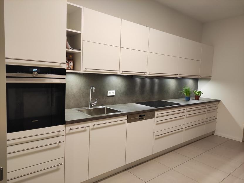 Einbauküche nach Maß von Tischlermeister Thorsten Reinhardt Moderne Einbauküche nach Maß mit weißen Fronten, dunkler Arbeitsplatte, integriertem Backofen und Spüle, sowie stilvoller Beleuchtung für eine hochwertige Küchenausstattung.