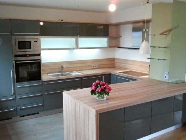 Küche mit Hochglanz-Grau und Holzarbeitsplatte von Tischlermeister Thorsten Reinhardt Moderne Küche mit hochglänzenden grauen Fronten, Holzarbeitsplatte und Kücheninsel, ausgestattet mit hochwertigen Geräten für eine stilvolle und praktische Küchengestaltung.