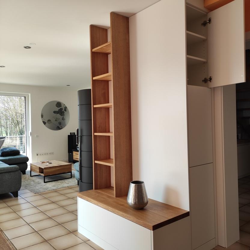 Maßgefertigtes Möbelstück als Raumteiler mit weißen Schränken, Holzregalen und Sitzbank, ideal für eine funktionale und stilvolle Wohnraumgestaltung.