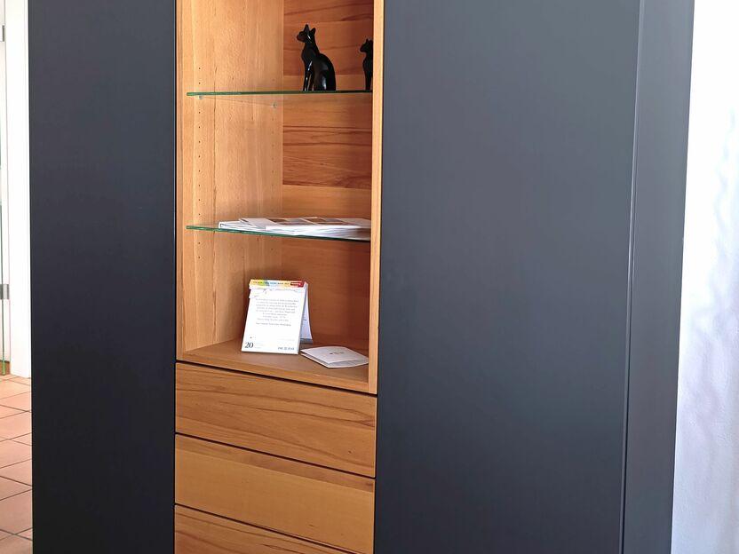 Modernes Hängeboard nach Maß mit schwarzen Fronten, offenen Holzfächern und Glaselementen, ideal für eine elegante und funktionale Wohnraumgestaltung.