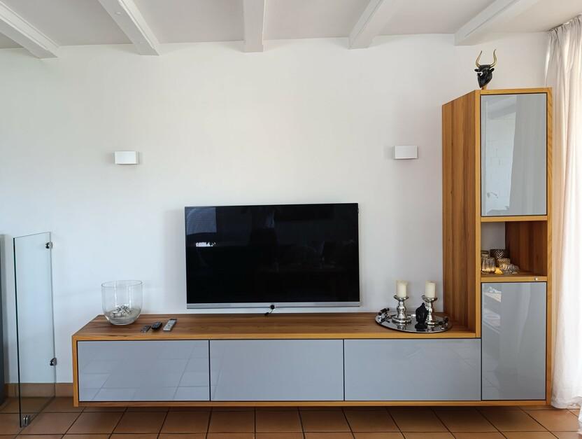 Stilvolle Fernsehwand nach Maß mit Holzakzenten, glänzenden grauen Fronten und offenen sowie geschlossenen Fächern, ideal für eine moderne Wohnraumgestaltung.