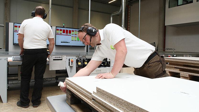 Zusammenarbeit zweier Arbeiter in Fertigungshalle bei CNC Produktion